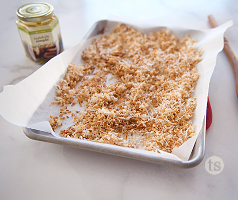 toasted coconut on baking sheet w/ Creamy Caramel in background