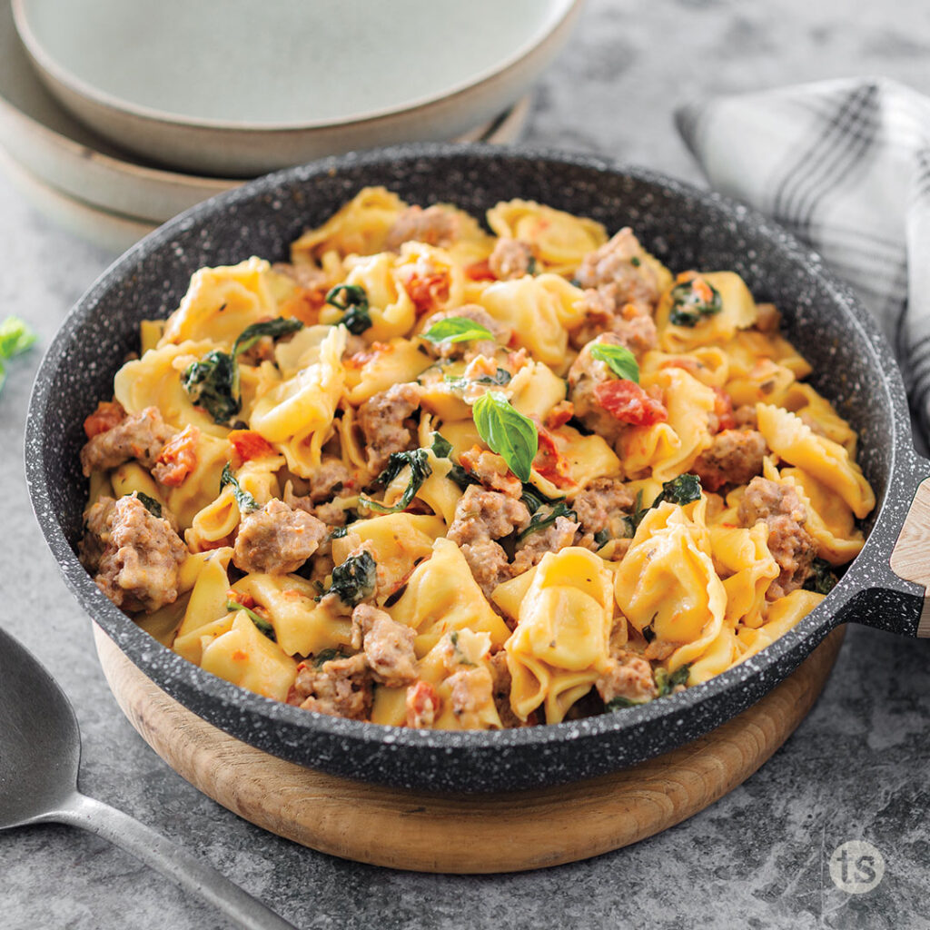 One skillet meal made with Tuscan Starter Sauce includes sausage, spinach and tortellini