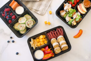 Bento boxes filled with meat, cheese, fruit, veggies, dips